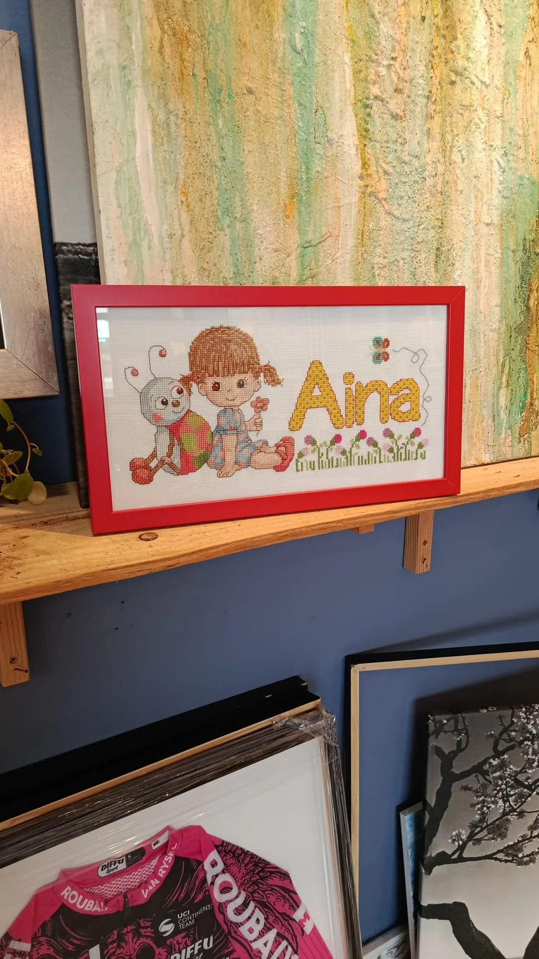 Punto de cruz Aina enmarcado con moldura roja en el taller Pepe Davent