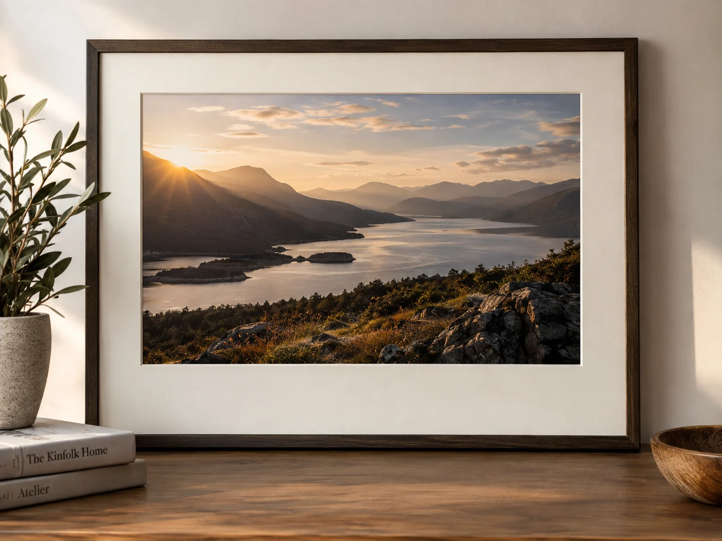 Paisaje de montañas y agua al atardecer, enmarcado con paspartú blanco y moldura de madera oscura.